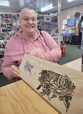 A person proudly showing a wooden board decorated with tiger artwork