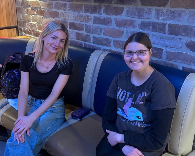 Two people smiling together on a bench during a bowling outing